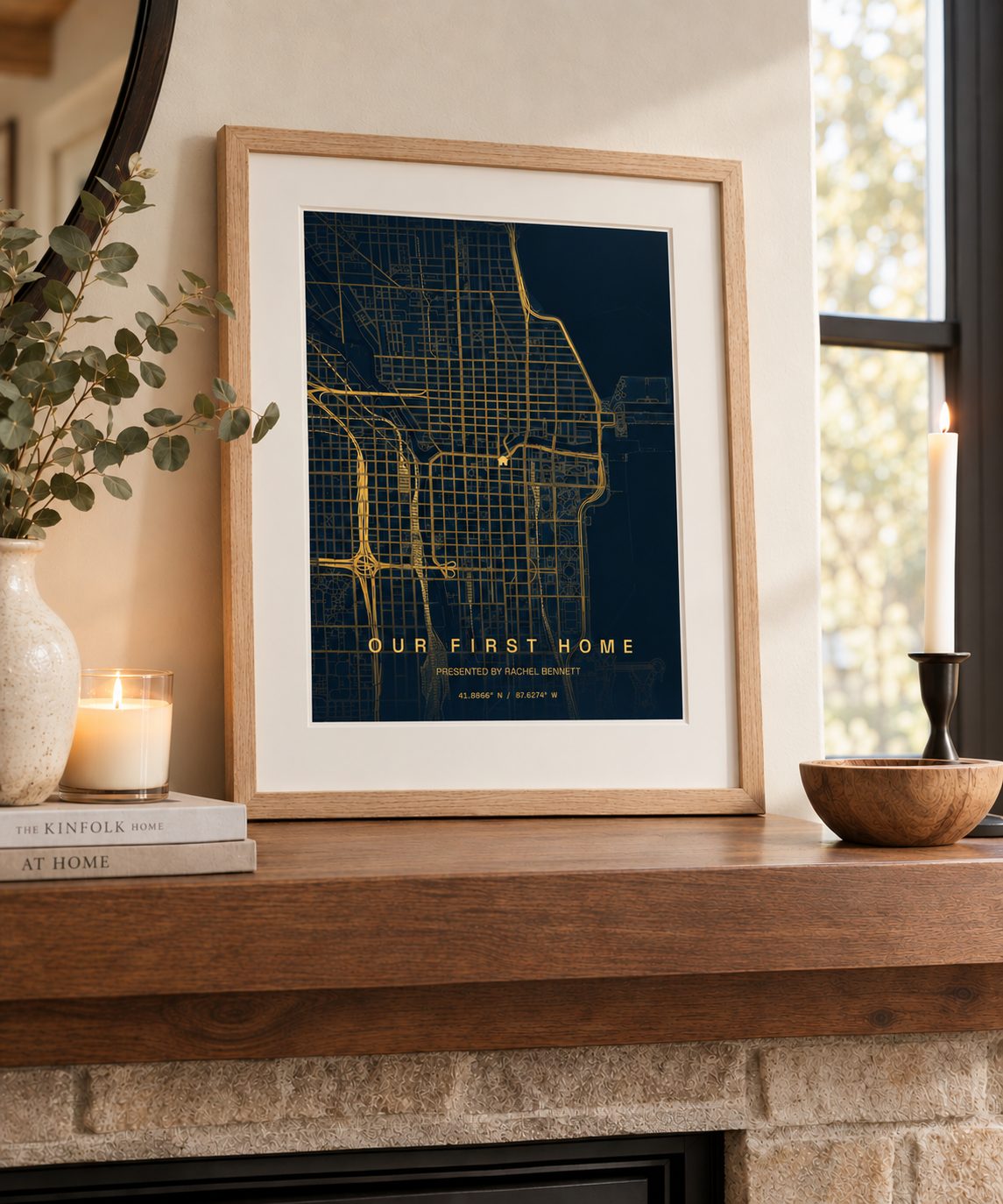 A framed LJ Map Co print of a first home, glowing on a candlelit mantel